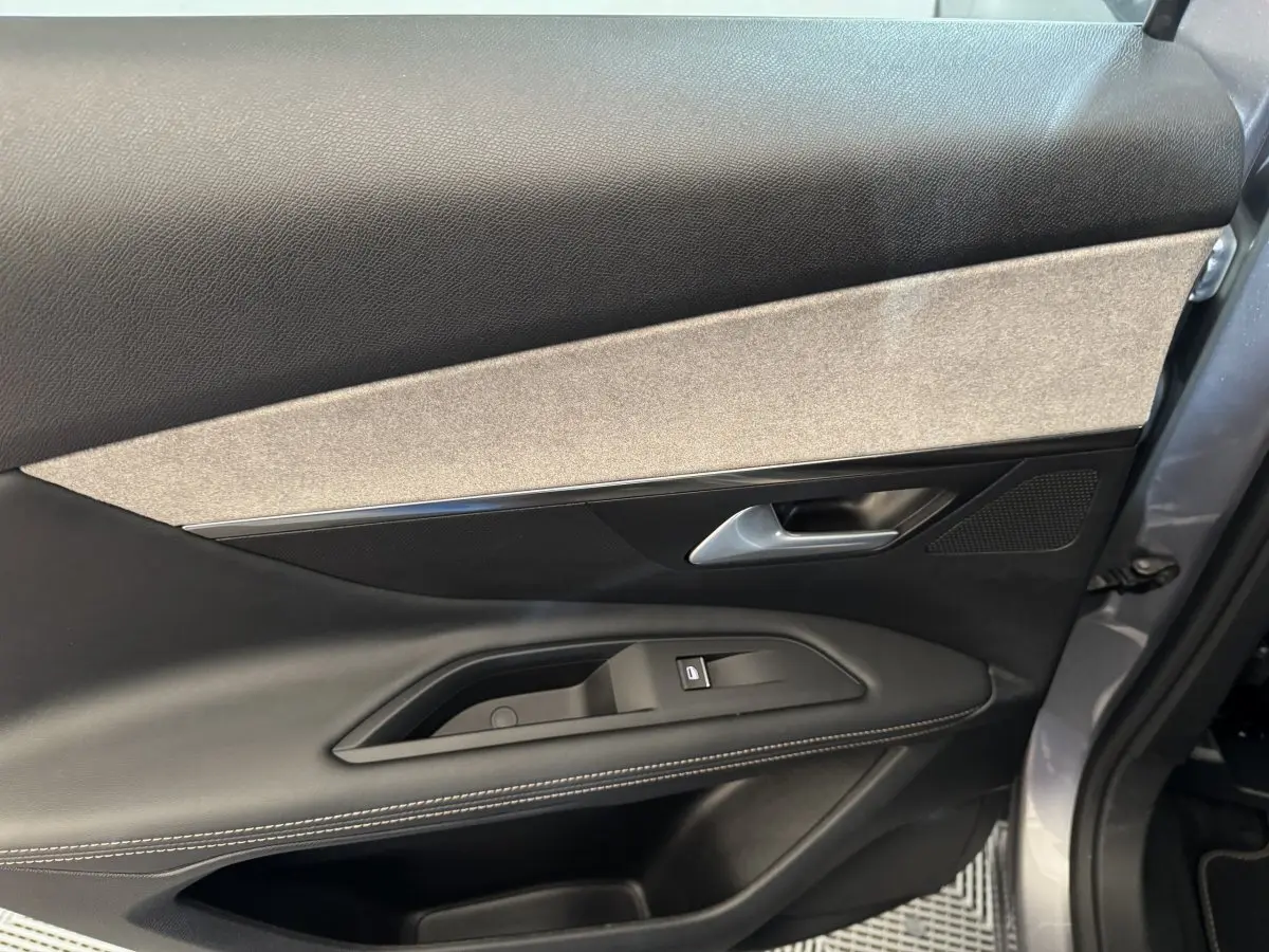 Vue rapprochée de la porte côté gauche gris clair du Peugeot 3008 2021 avec garniture noire et beige et commande de vitre.