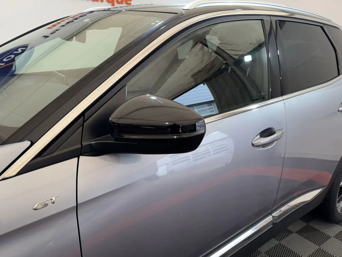 Vue côté gauche avant du Peugeot 3008 GT gris clair avec rétroviseur noir et badge GT sur la porte.