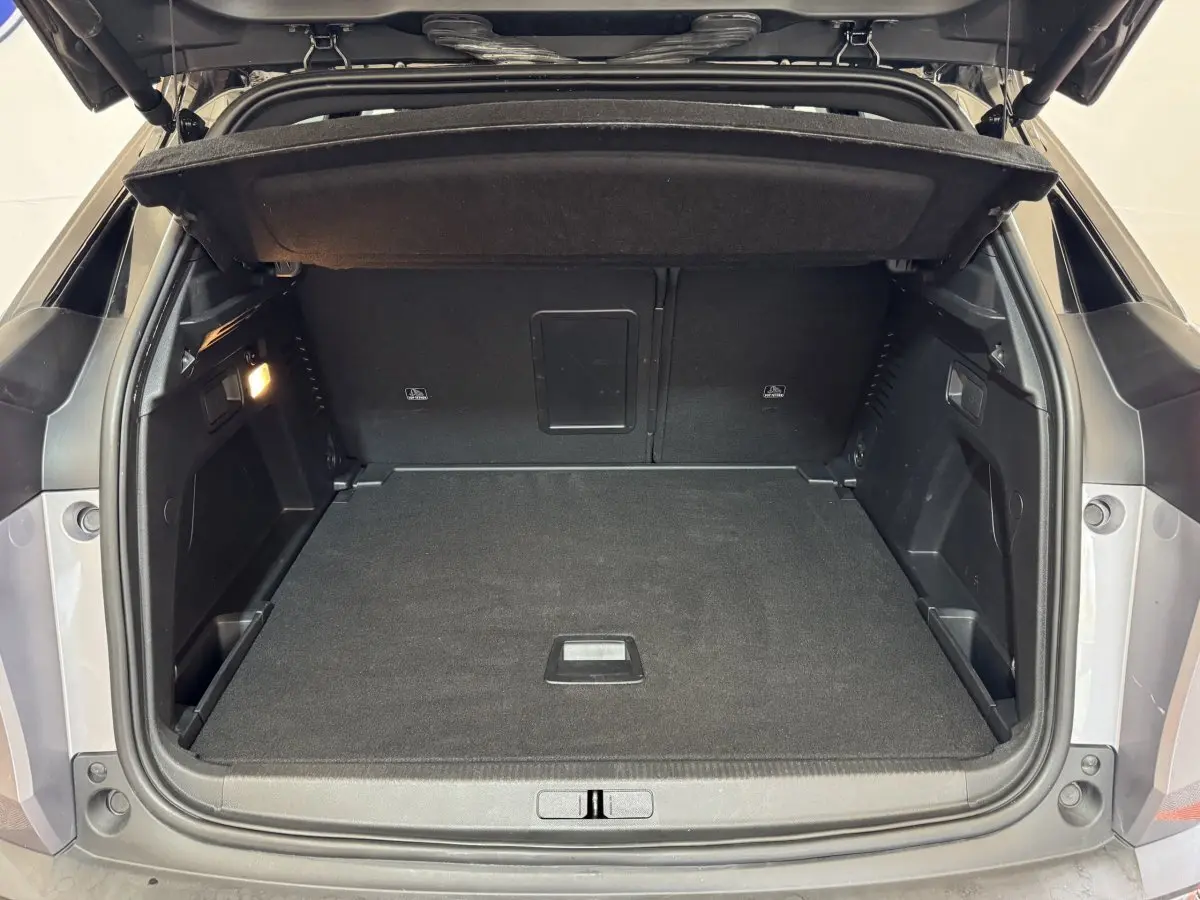 Coffre ouvert vu de l'arrière d'un Peugeot 3008 gris clair, montrant un espace de chargement propre et spacieux.