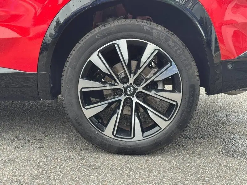 Gros plan sur la roue avant droite du Renault Austral rouge Flamme avec jante alu bicolore noire et argent.