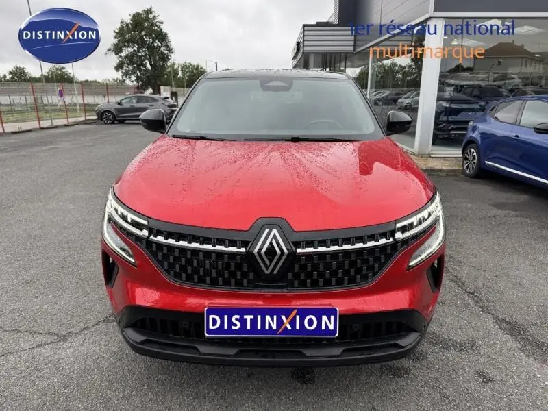 Vue avant d’un Renault Austral rouge Flamme avec toit noir étoilé, calandre noire et logo Renault central.