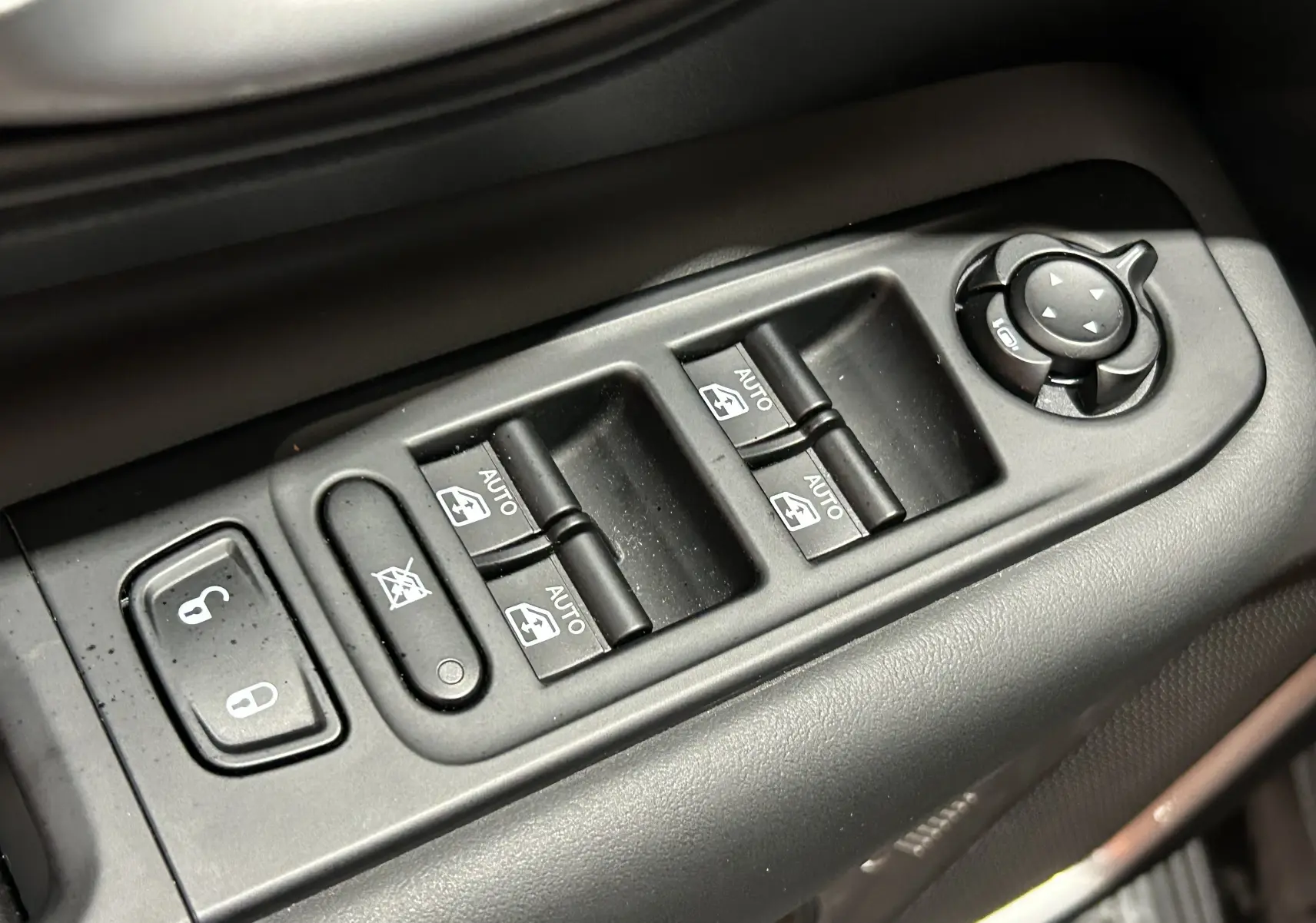 Gros plan sur les commandes de lève-vitres et rétroviseurs côté conducteur du Jeep Renegade 2023 gris graphite.