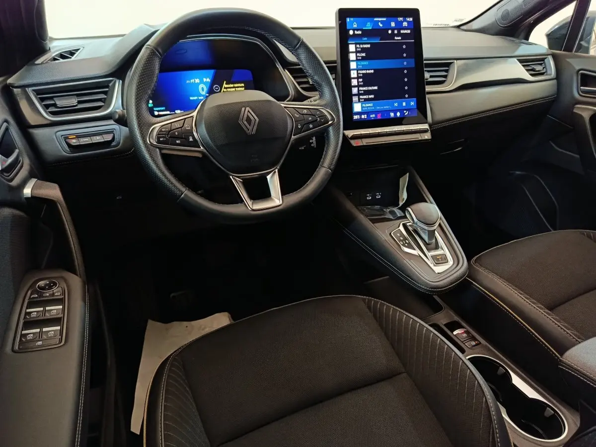 Vue intérieure avant du Renault SYMBIOZ 2025, tableau de bord noir avec écran tactile vertical et volant multifonctions.