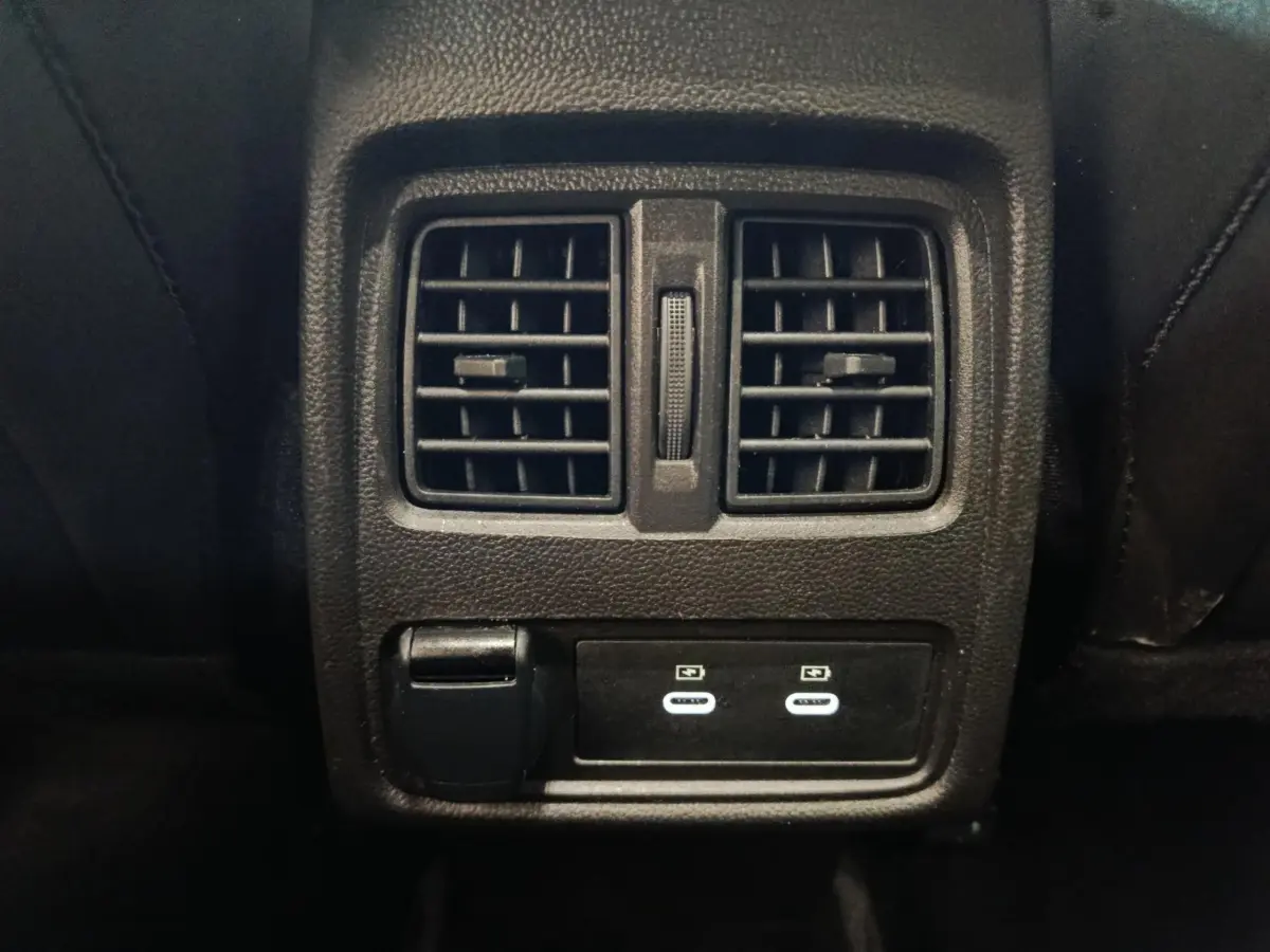 Gros plan sur la console arrière noire du Renault Symbioz avec bouches d’aération et ports USB-C éclairés.