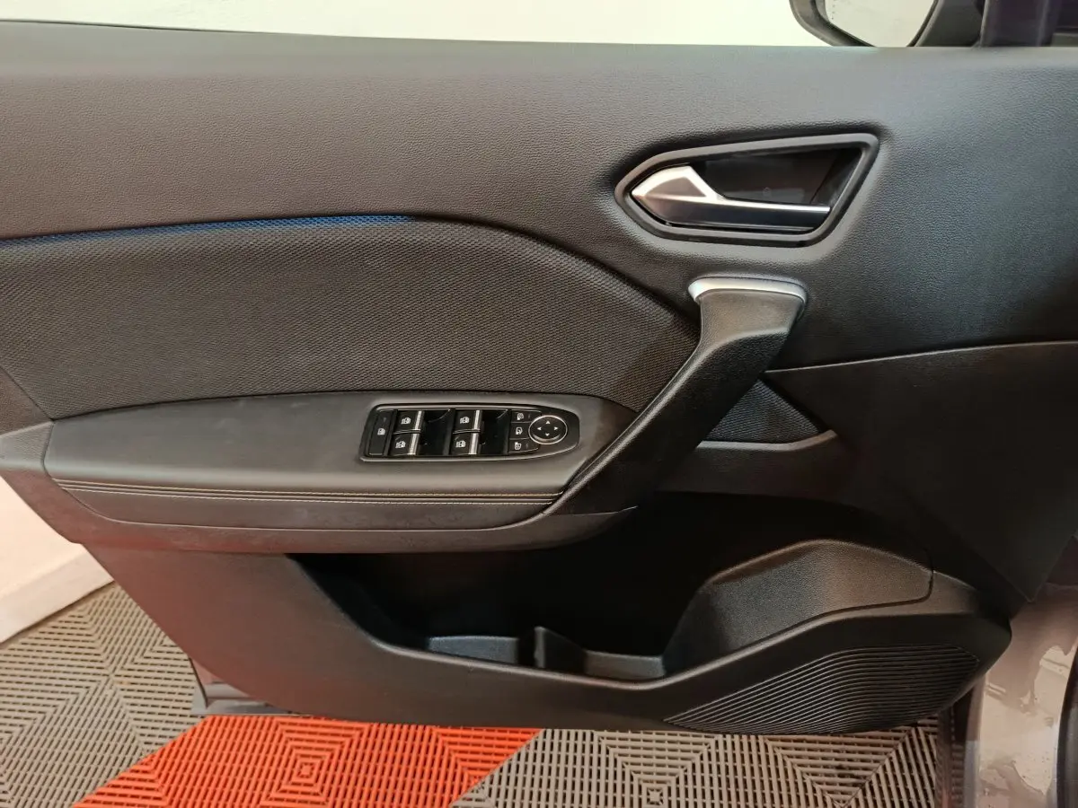 Vue intérieure du panneau de porte avant gauche de la Renault Symbioz 2025, avec commandes de vitres et poignée noire.