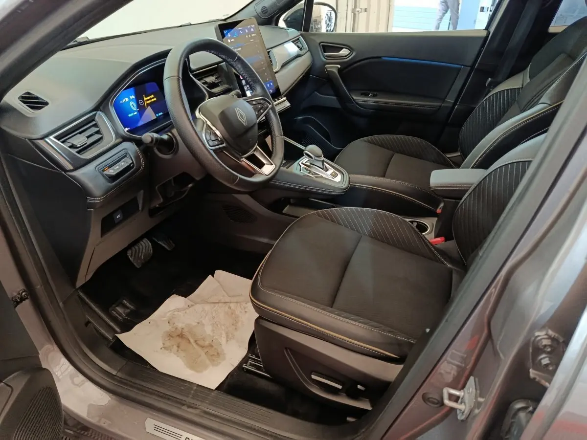 Vue intérieure côté conducteur du Renault Symbioz 2025, sièges noirs et tableau de bord avec écran tactile vertical.