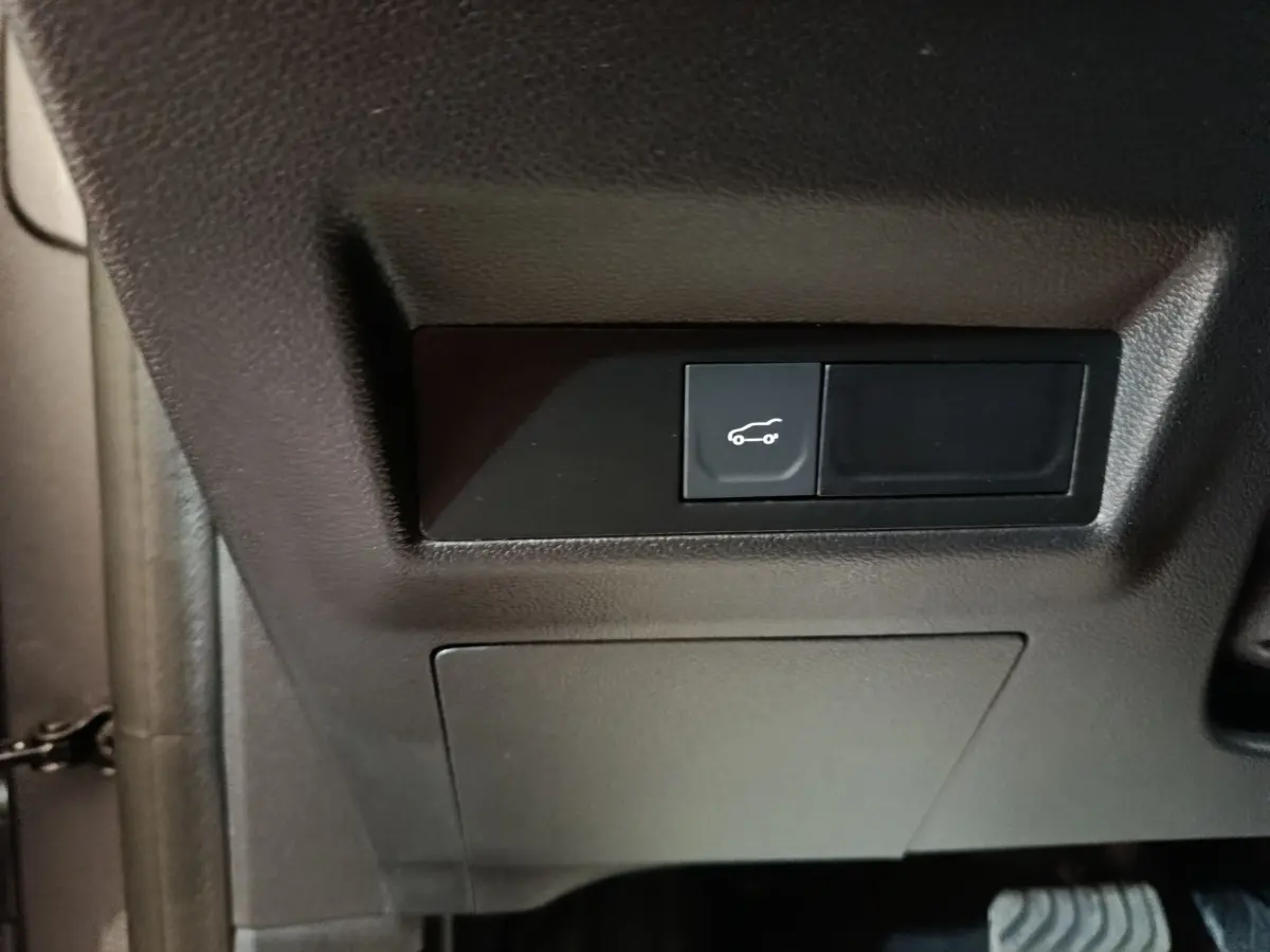 Bouton d'ouverture du coffre noir sur tableau de bord intérieur côté conducteur d'une Renault Symbioz hybride 2025.