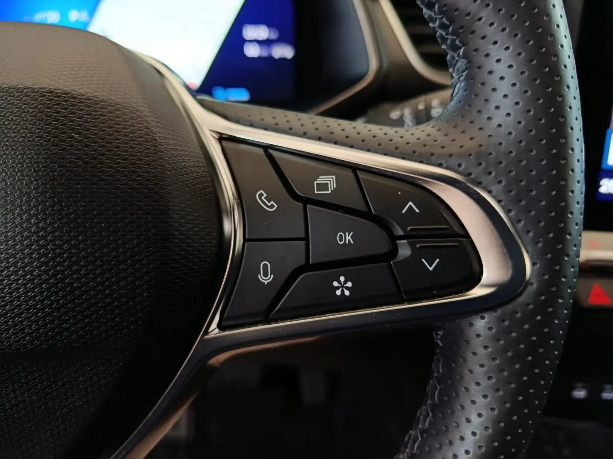 Gros plan sur les commandes multifonctions à droite du volant perforé noir du Renault Symbioz 2025 hybride.