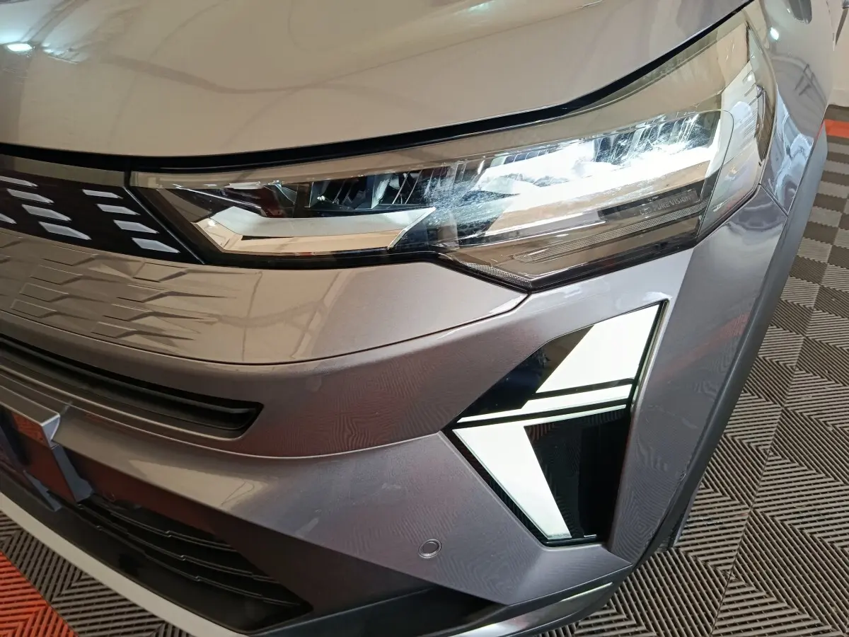 Gros plan sur l'avant droit gris métallisé du Renault Symbioz 2025, mettant en valeur ses phares LED et feux de jour distinctifs.