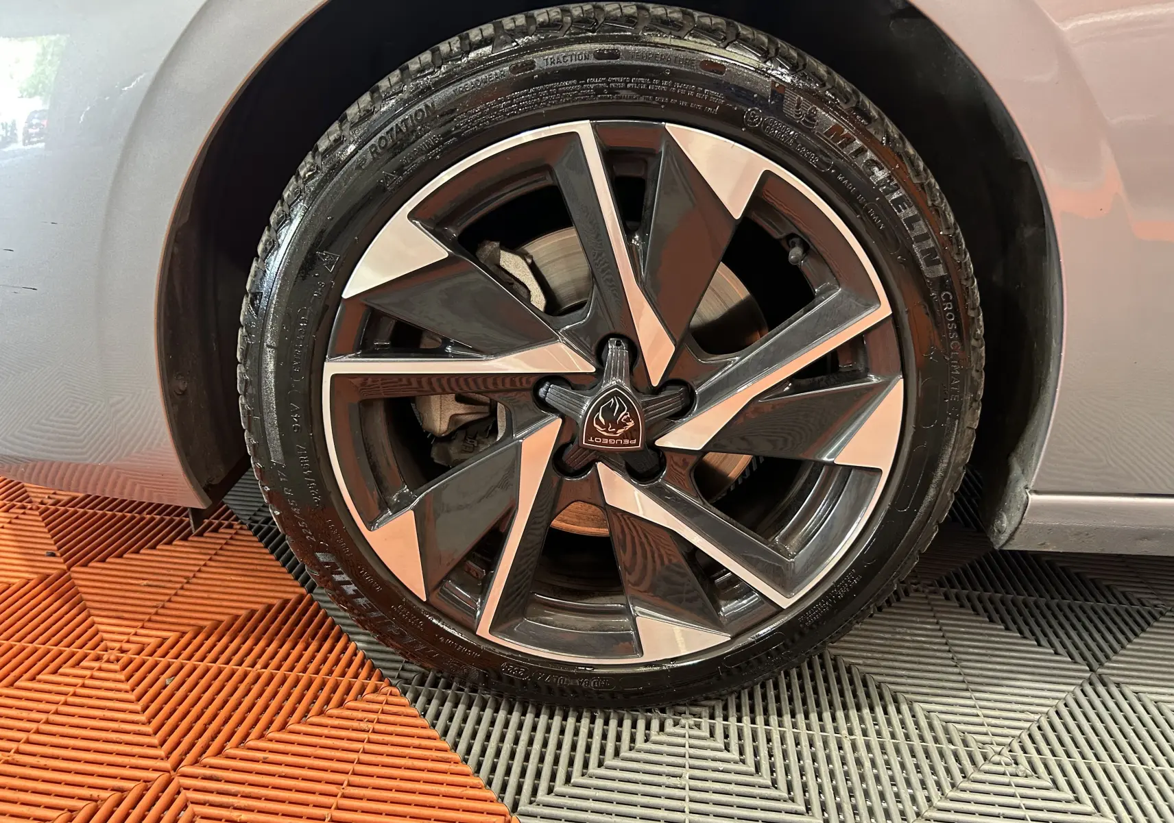 Gros plan sur la roue avant droite d'une Peugeot 308 gris 2022 avec jante alliage noire et argentée au design géométrique.