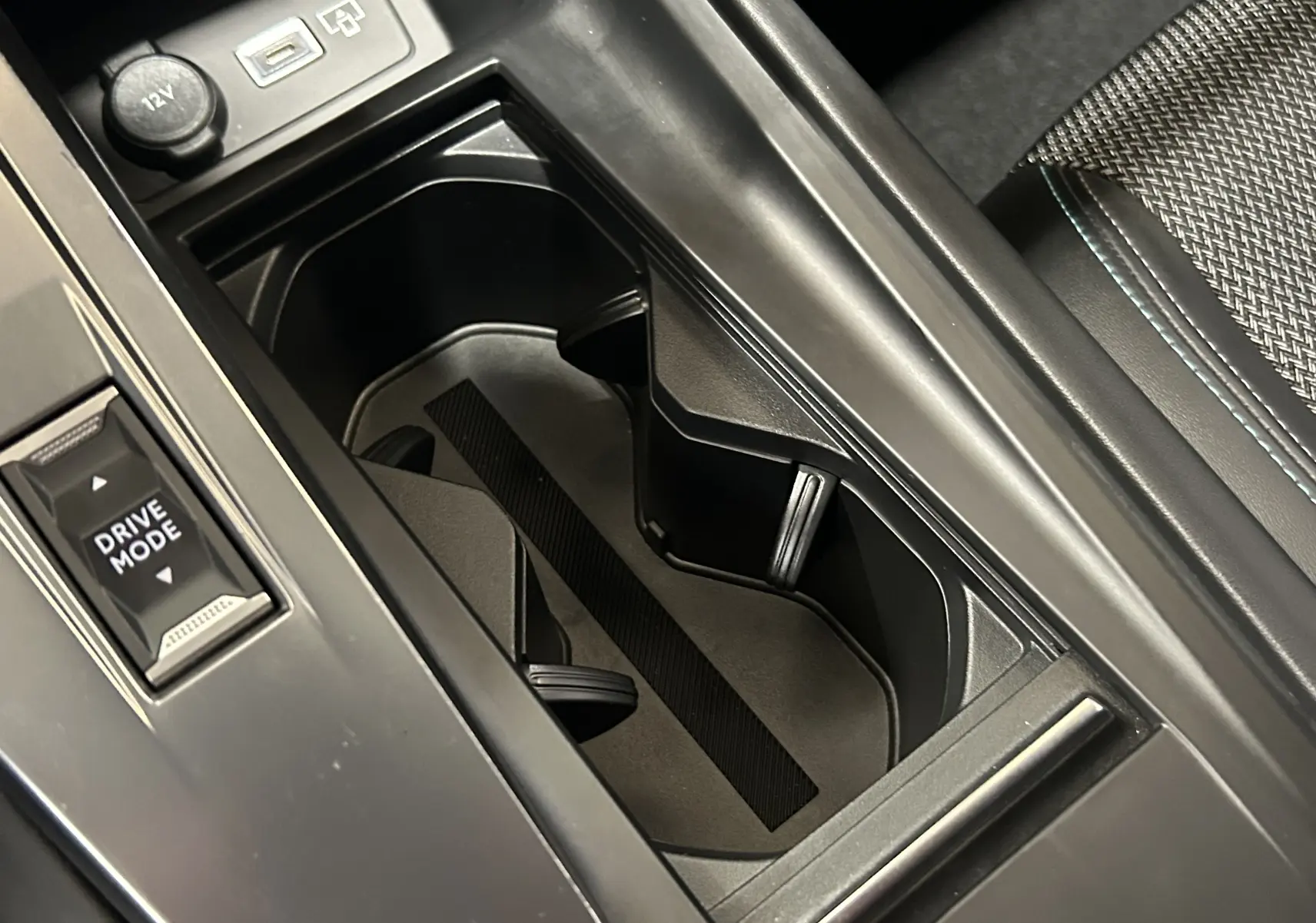 Gros plan sur le porte-gobelets central noir et bouton Drive Mode dans l’habitacle de la Peugeot 308 gris 2022.