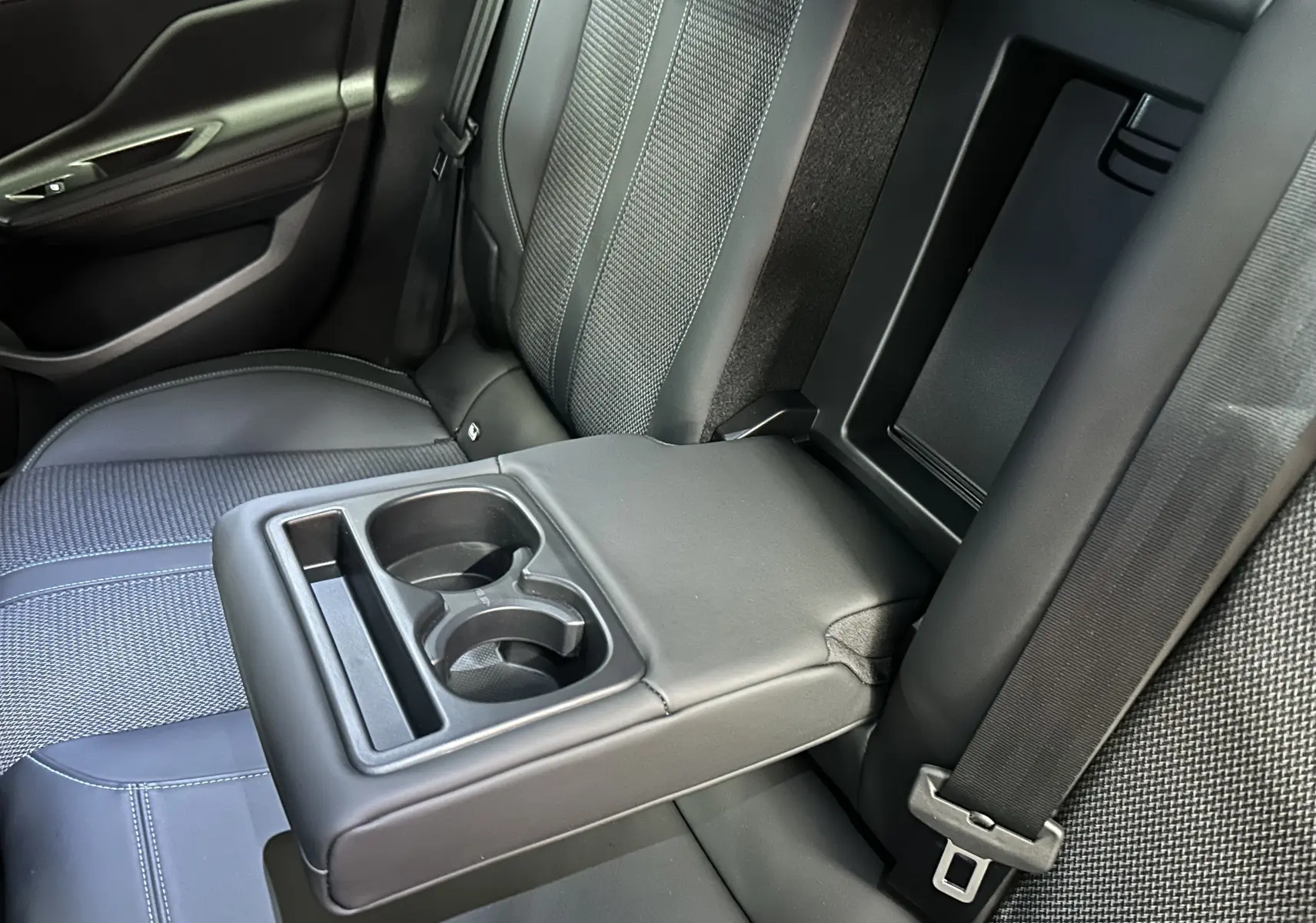 Vue rapprochée de l'accoudoir central arrière gris avec porte-gobelets dans l'habitacle de la Peugeot 308 2022.