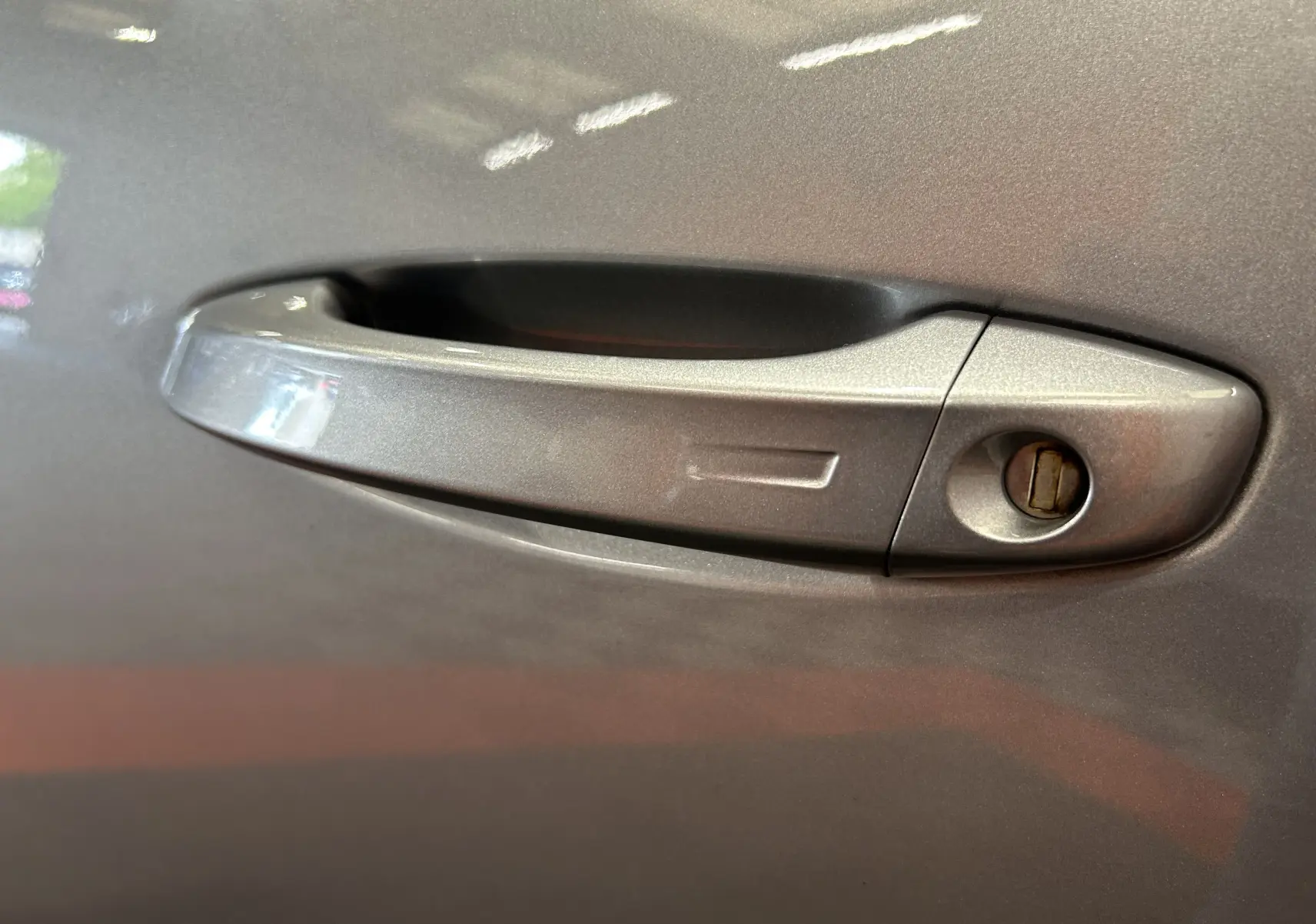 Poignée de porte gris métallisé de Peugeot 308 BlueHDi 130ch, vue en gros plan sur la serrure côté droit.