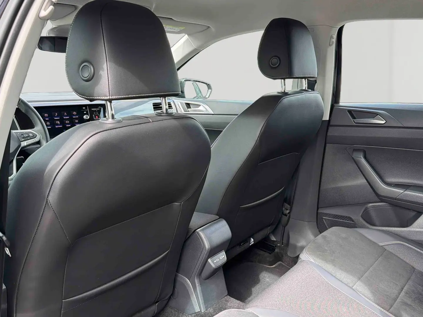 Vue arrière intérieure de la Volkswagen Polo 2025 noire, montrant les sièges avant en cuir et la console centrale.