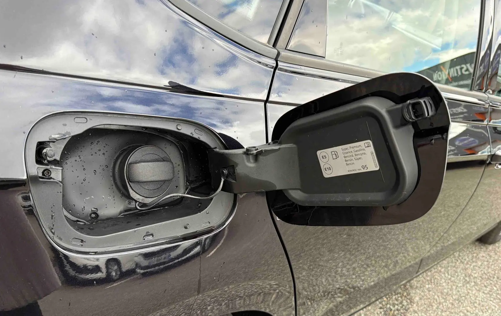 Vue rapprochée de la trappe à carburant ouverte côté gauche d'une Volkswagen Polo noire 2025.