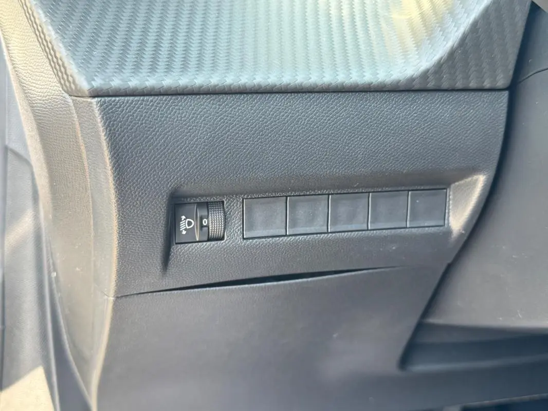 Détail du tableau de bord côté gauche d’une Peugeot 208 gris, montrant le réglage des phares.