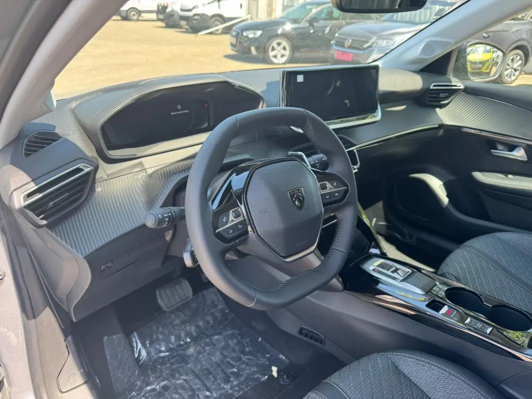 Vue intérieure côté conducteur du Peugeot 208 Hybrid 110 gris, avec volant compact et écran tactile central.