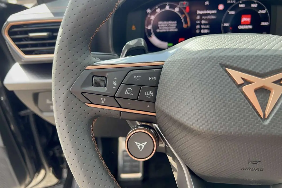 Gros plan sur le volant cuir perforé du Cupra Formentor noir minuit, avec commandes multifonctions et logo Cupra cuivré.