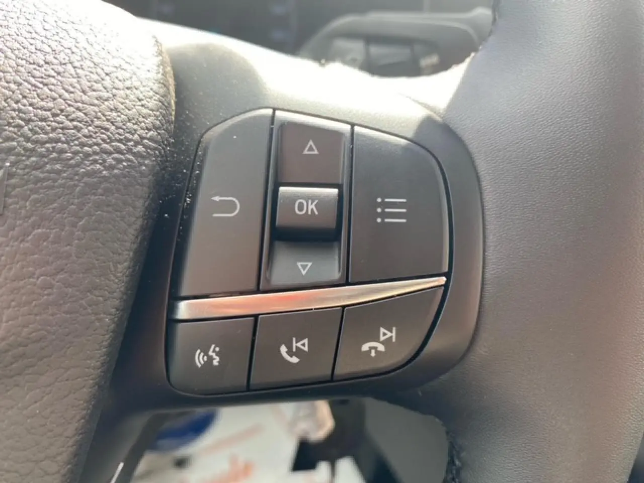 Gros plan sur les commandes multifonctions à gauche du volant du Ford Transit Fourgon blanc 2023.