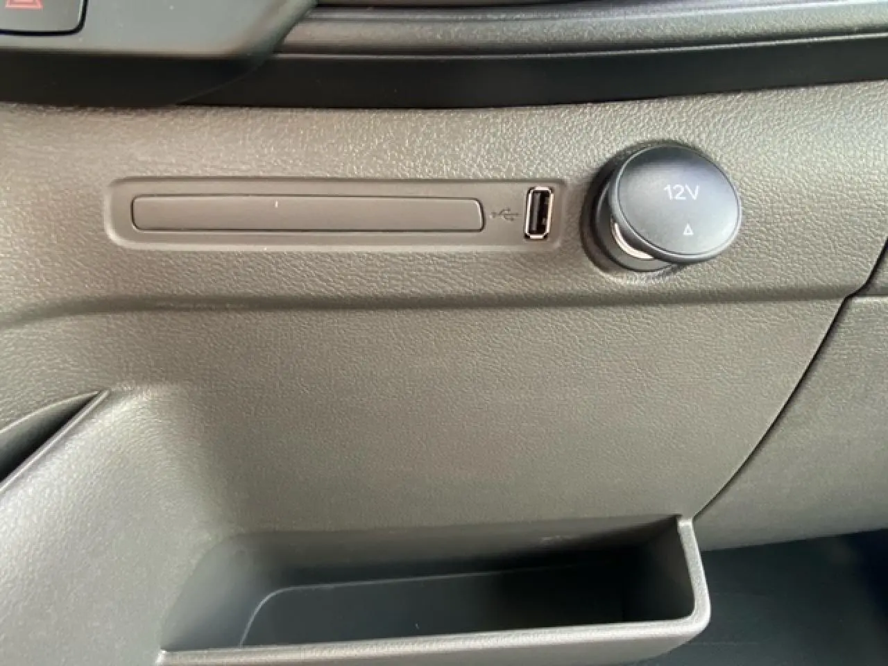 Prise USB et allume-cigare 12V en gros plan sur la console intérieure grise du Ford Transit Fourgon blanc 2023.