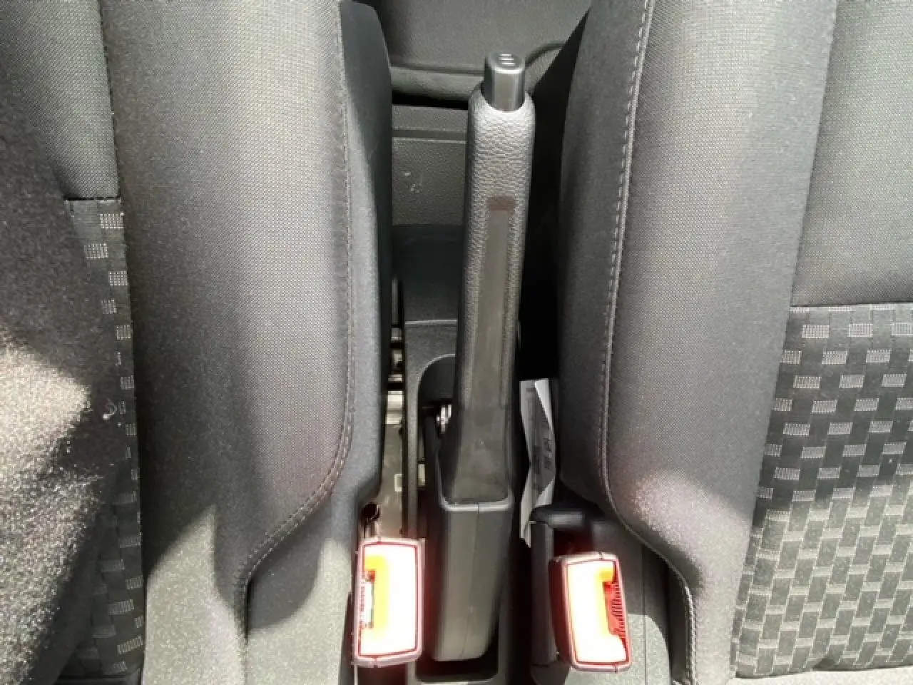 Vue rapprochée du frein à main et des ceintures de sécurité entre les sièges avant du Ford Transit Fourgon blanc 2023.