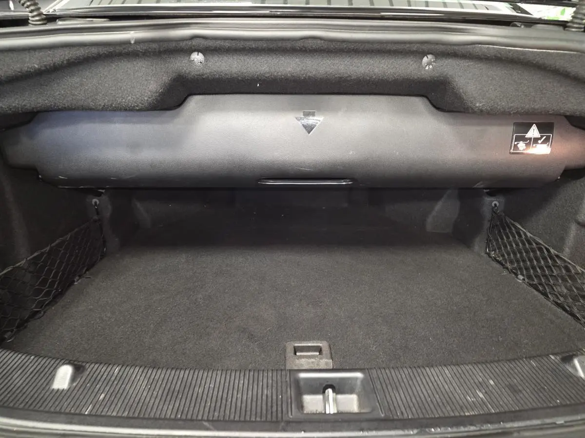Coffre ouvert noir de la Mercedes Classe E Cabriolet E 250 CDI Fascination, montrant l'espace de rangement vide et les filets latéraux.