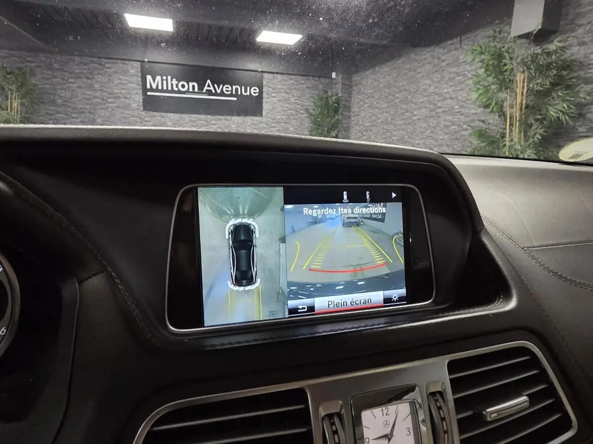 Vue intérieure du tableau de bord d'une Mercedes Classe E Cabriolet noire, écran multimédia affichant la caméra 360° en marche.