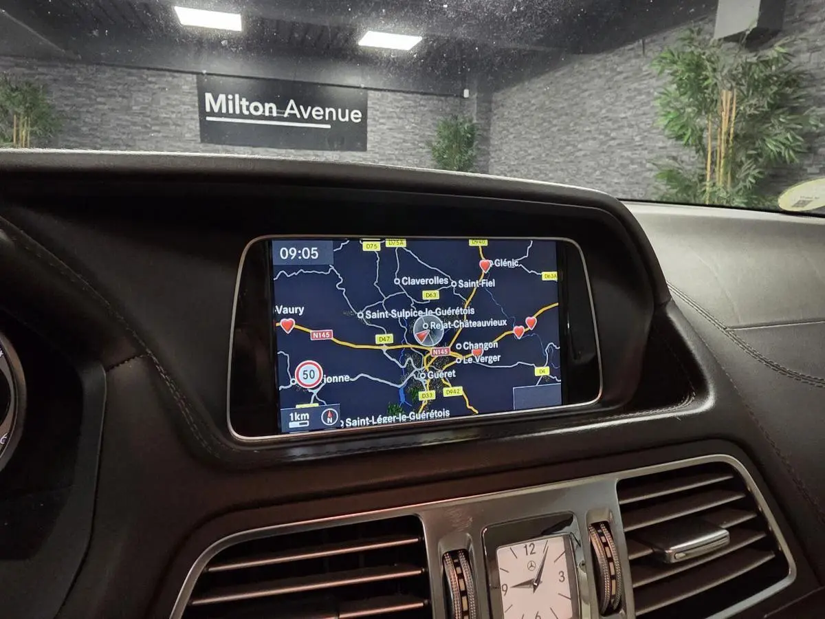 Vue rapprochée de la console centrale cuir noir avec écran GPS et horloge analogique Mercedes-Benz intégrée.