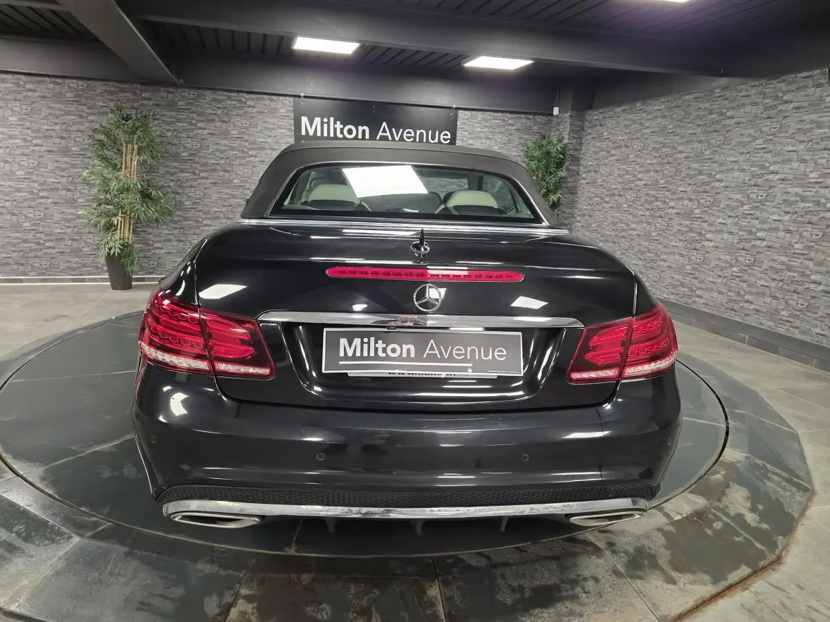 Vue arrière d'un cabriolet Mercedes Classe E noir avec double sortie d'échappement et feux arrière LED allumés.