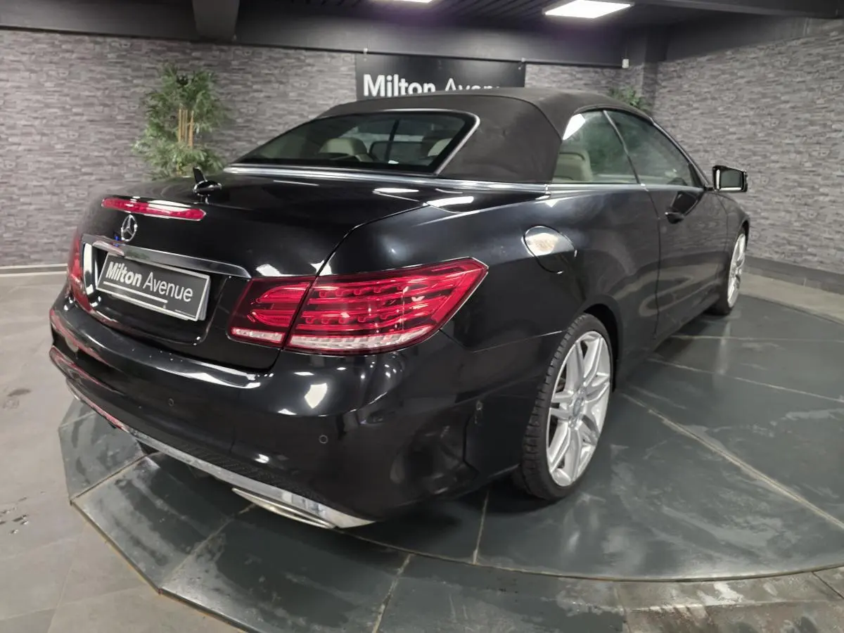 Vue 3/4 arrière droite d'une Mercedes Classe E Cabriolet noire avec capote fermée et jantes alliage AMG 19 pouces.