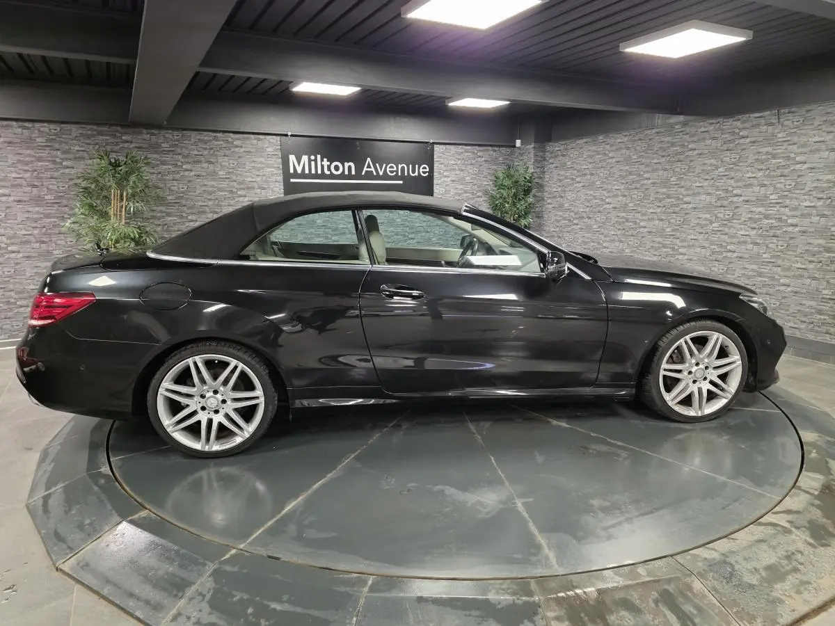 Mercedes Classe E Cabriolet noir vue de profil côté gauche avec capote fermée et jantes alliage visibles.