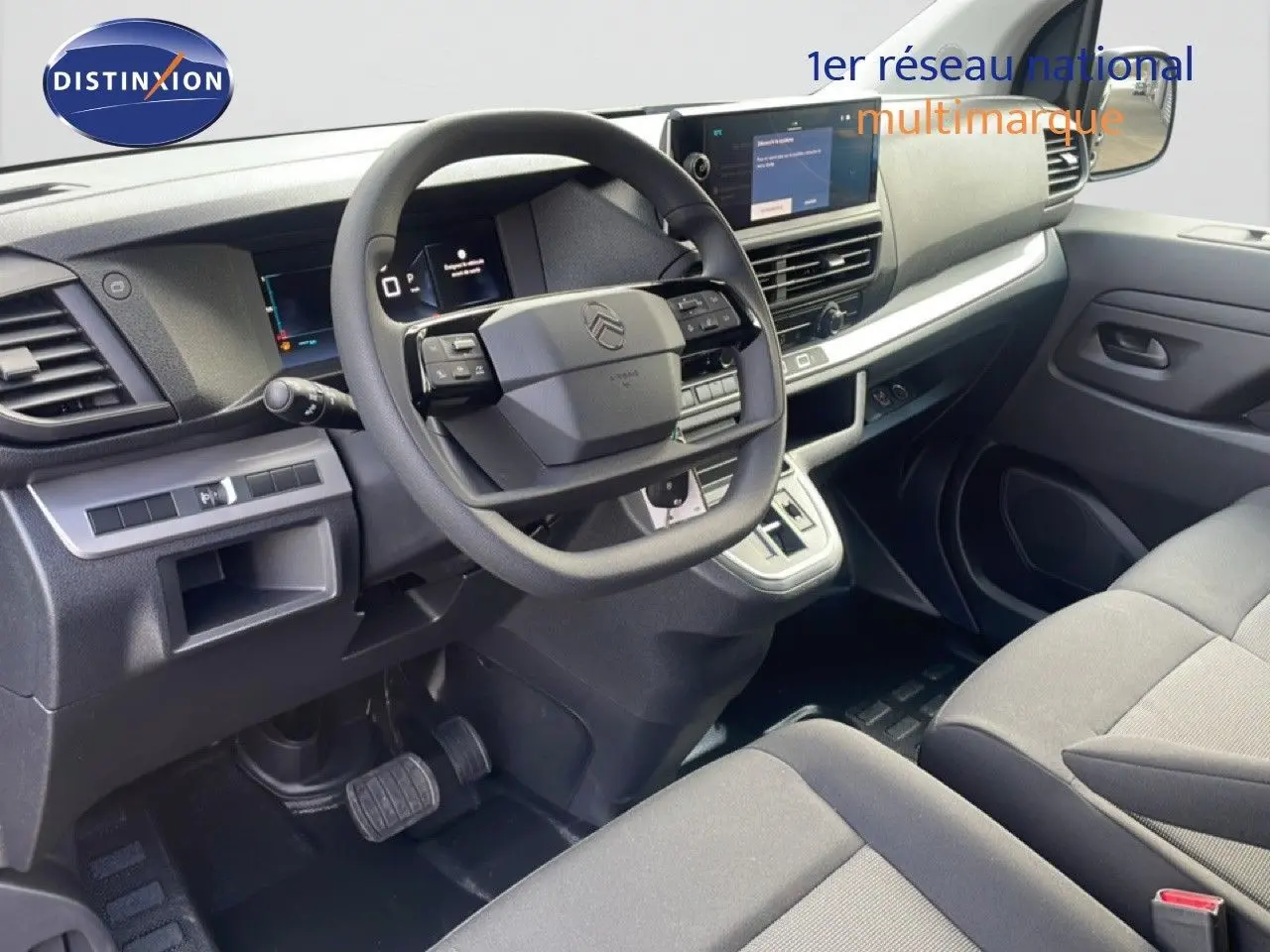 Vue intérieure côté conducteur du Citroën Jumpy 2025 avec tableau de bord moderne et sièges en tissu gris.