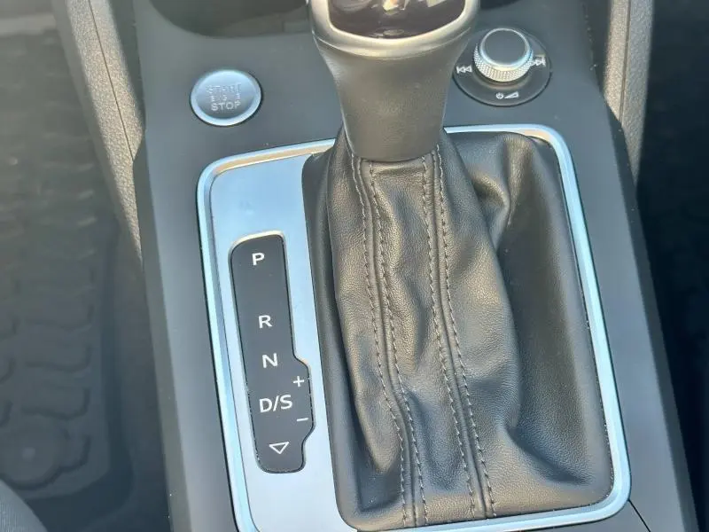 Gros plan sur la console centrale de l'Audi Q2 35 TFSI blanc, montrant le levier de vitesses automatique et le bouton start/stop.