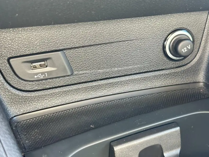 Gros plan sur la prise USB et la prise 12V intégrées dans la console centrale noire de l'Audi Q2 blanc 35 TFSI 2023.