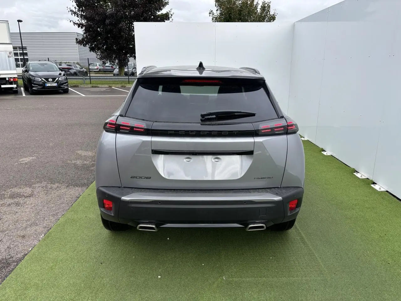 Vue arrière du Peugeot 2008 gris Artense avec toit noir, feux arrière LED à 3 griffes et double sortie d’échappement chromée.