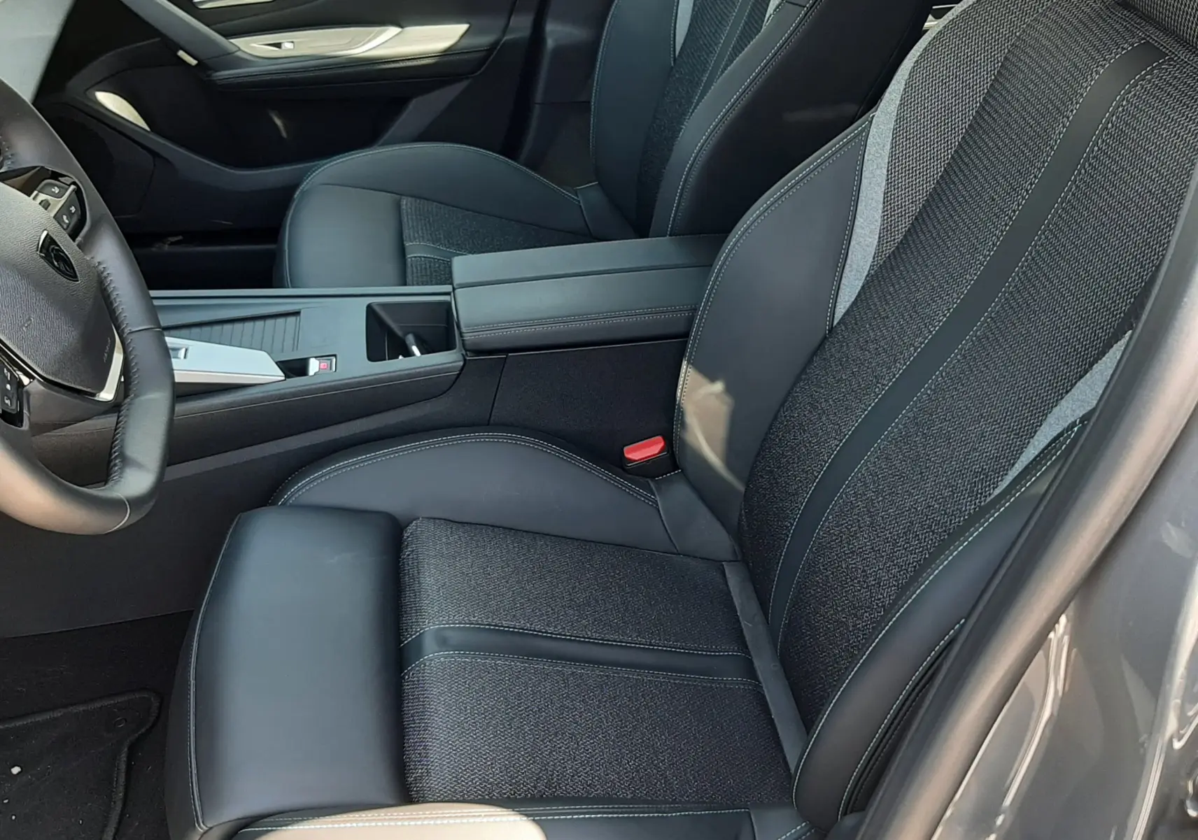 Vue intérieure côté conducteur du Peugeot 408 gris selenium 2024, sièges en tissu et cuir noir avec surpiqûres contrastées.