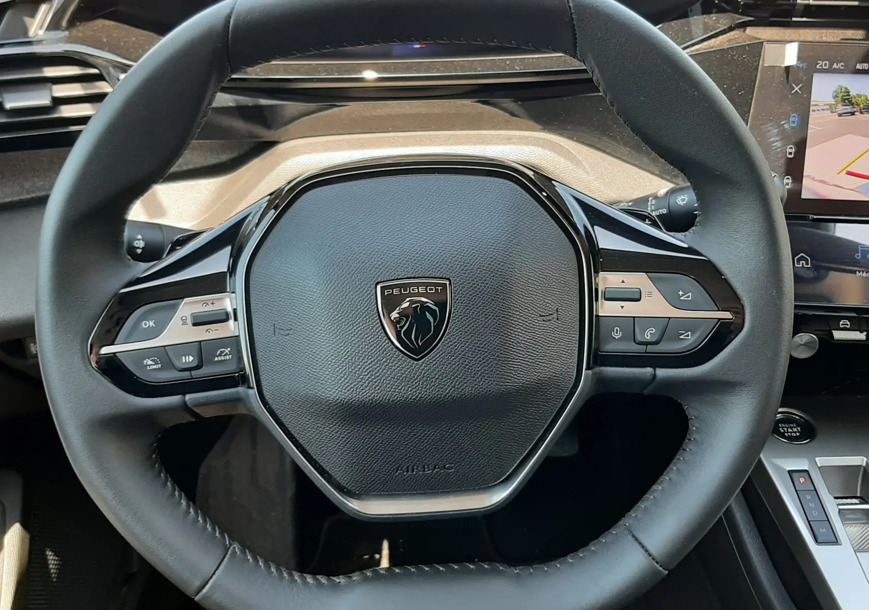 Vue rapprochée du volant cuir noir du Peugeot 408 Hybrid 2024 avec commandes intégrées et tableau de bord numérique.