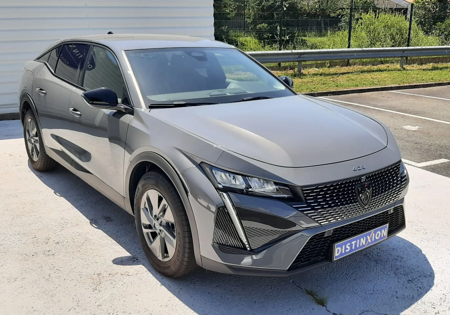 Peugeot 408 gris sélénium vue 3/4 avant droit, mettant en valeur sa calandre moderne et ses phares LED distinctifs.