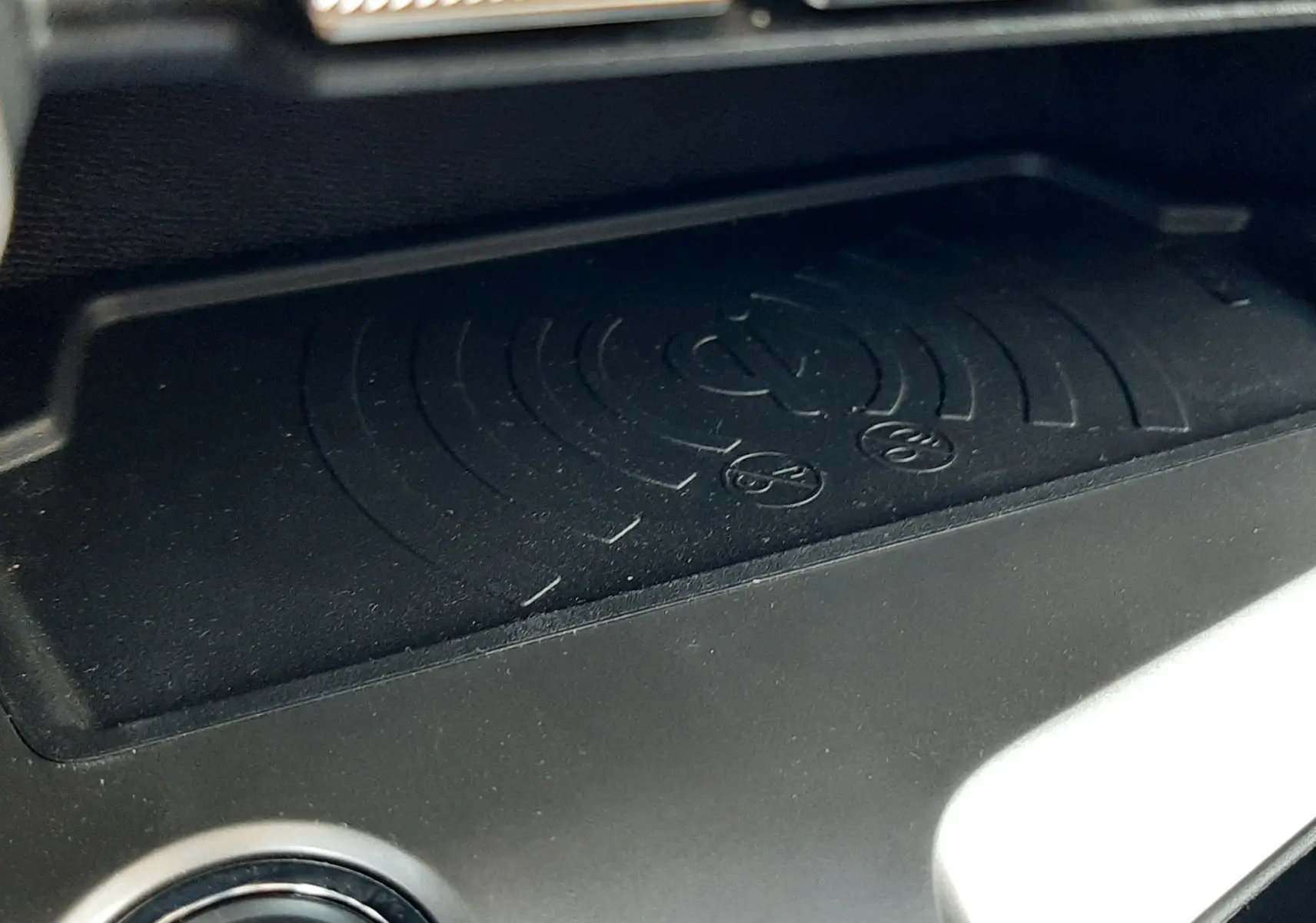 Détail du plateau de recharge sans fil et bouton start/stop dans l'habitacle de la Peugeot 408 Hybrid gris selenium, vue rapprochée.
