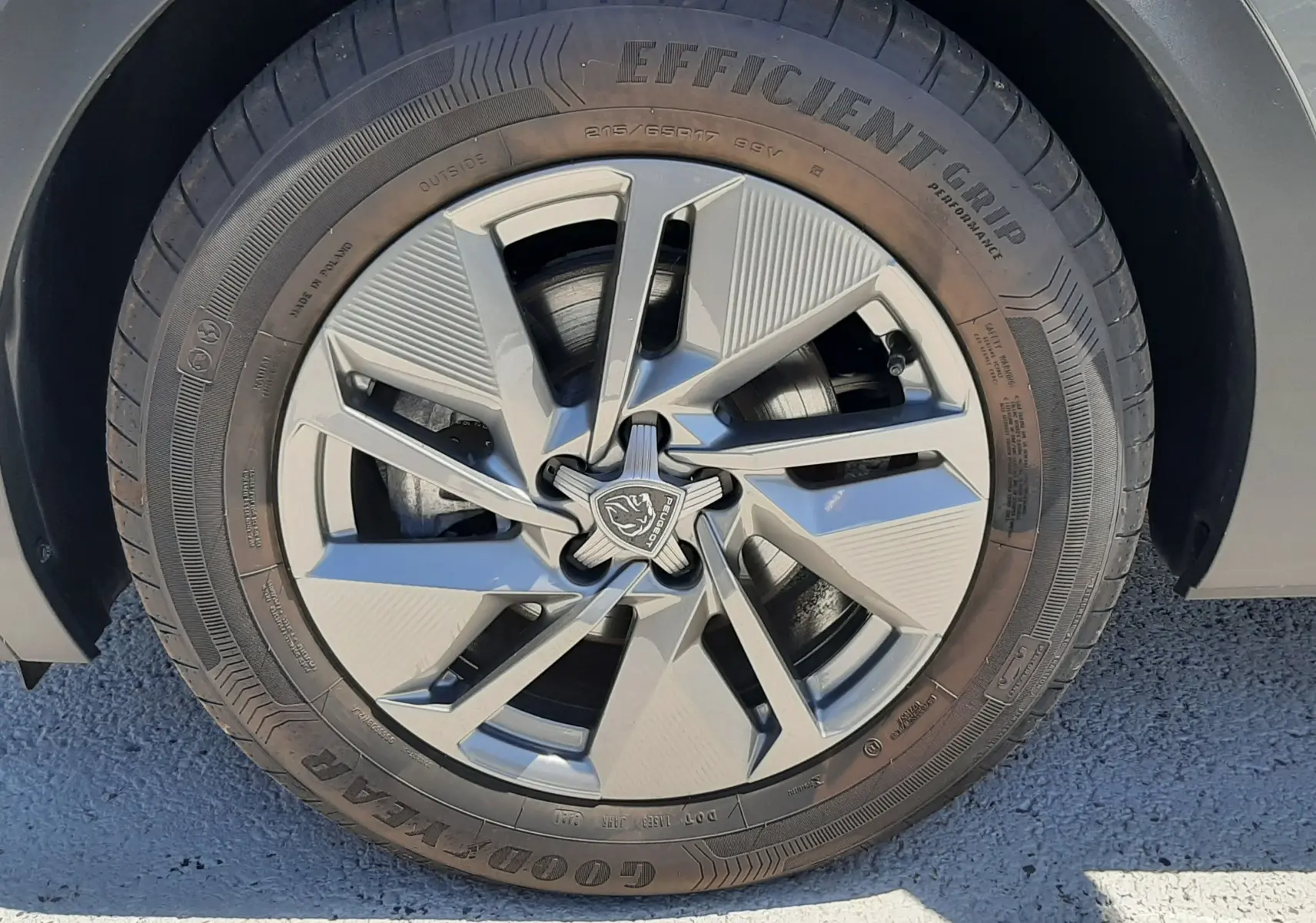 Gros plan sur la roue avant droite gris selenium d'une Peugeot 408 Hybrid 145ch avec jante alliage et logo lion central.