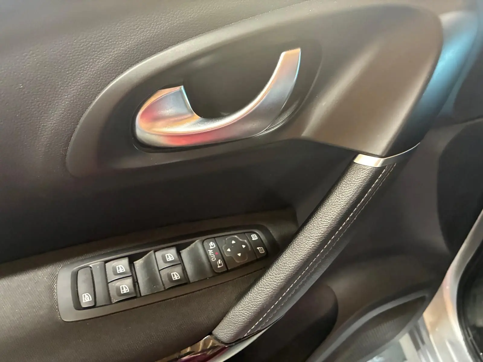 Gros plan sur la poignée intérieure et les commandes des vitres côté conducteur du Renault Kadjar gris 2020.