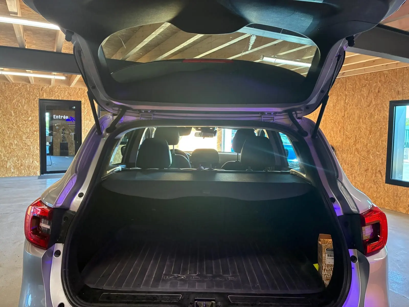 Vue arrière ouverte du Renault Kadjar gris 2020, coffre spacieux avec tapis de protection et intérieur noir visible.