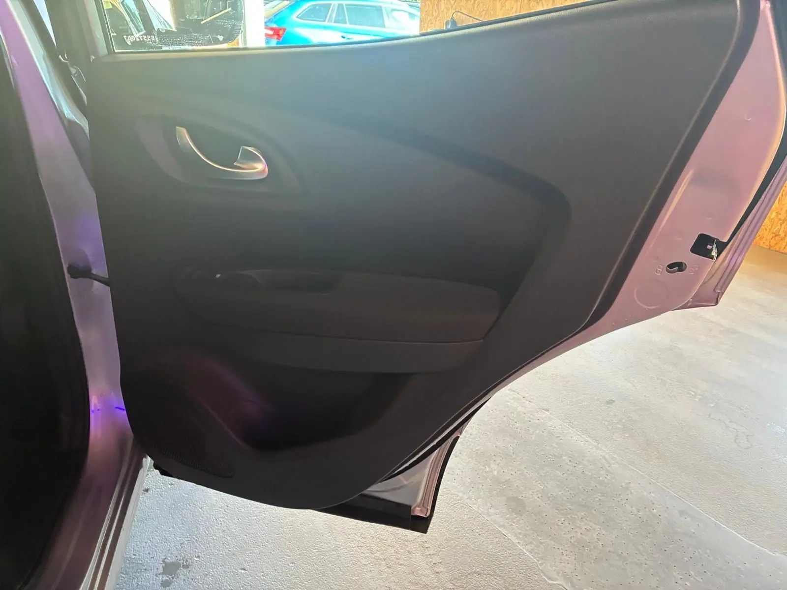 Vue rapprochée de la porte arrière gauche ouverte du Renault Kadjar gris, montrant la garniture intérieure noire.