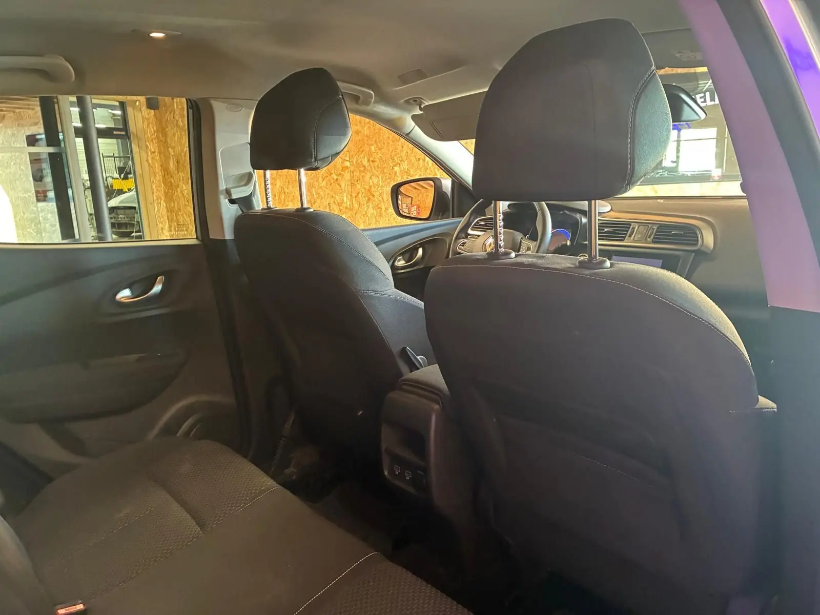 Vue intérieure arrière du Renault Kadjar gris 2020, montrant les sièges avant en tissu noir et la console centrale.