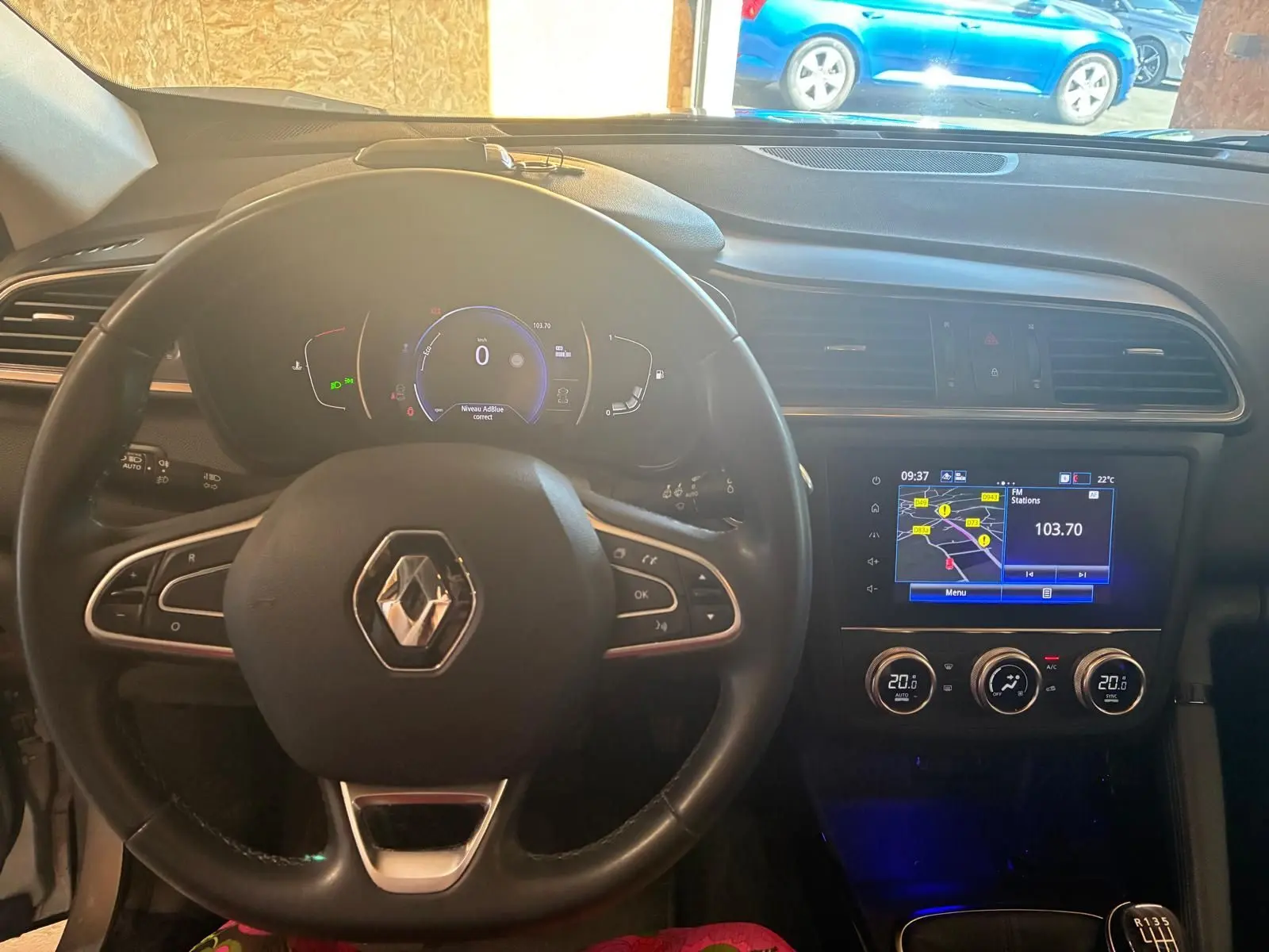 Vue intérieure centrée sur le volant Renault et le tableau de bord avec écran tactile et climatisation digitale du Kadjar gris.