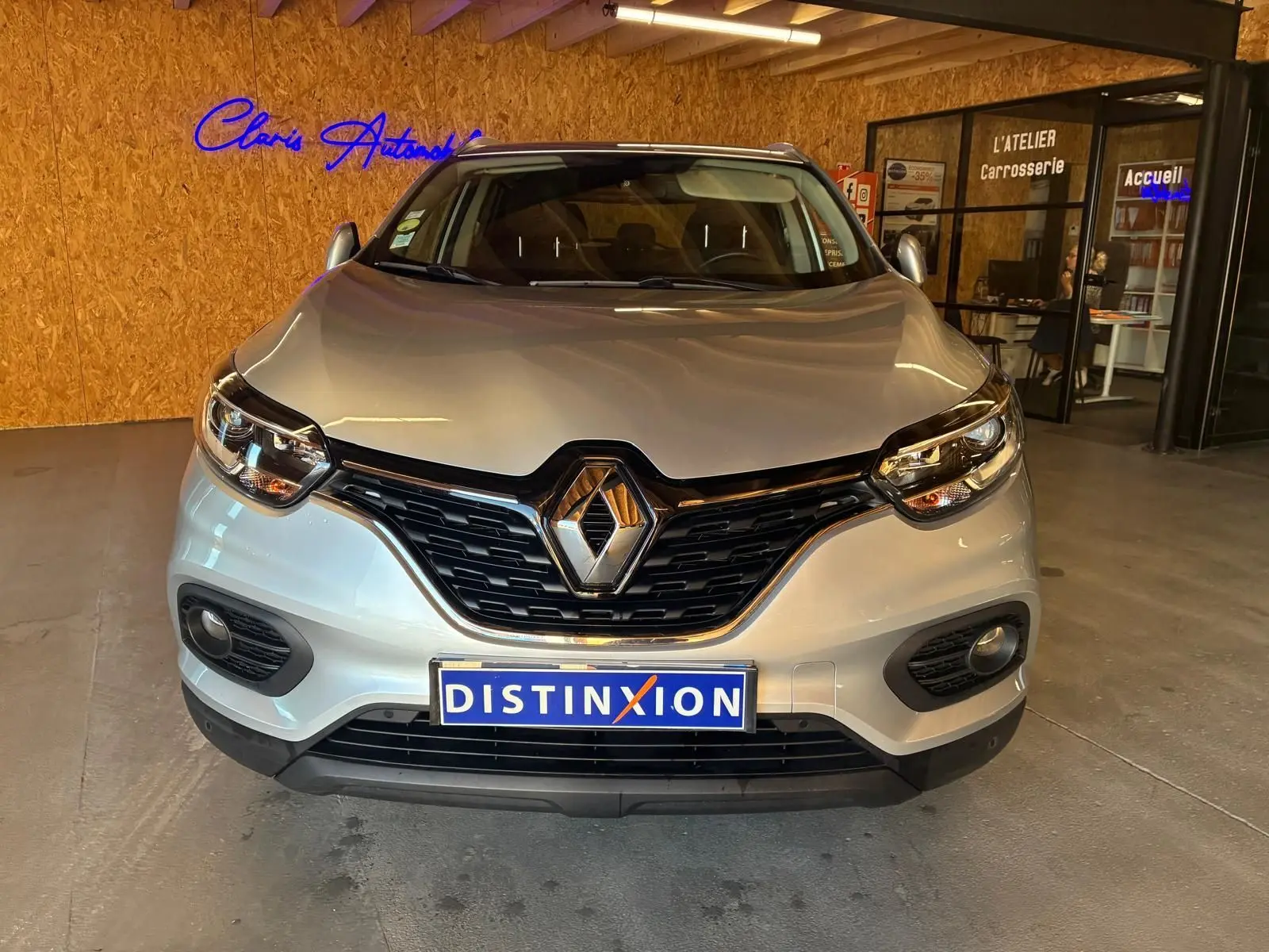 Vue de face d'un Renault Kadjar gris 2020, mettant en valeur la calandre noire et les phares LED dans un showroom.