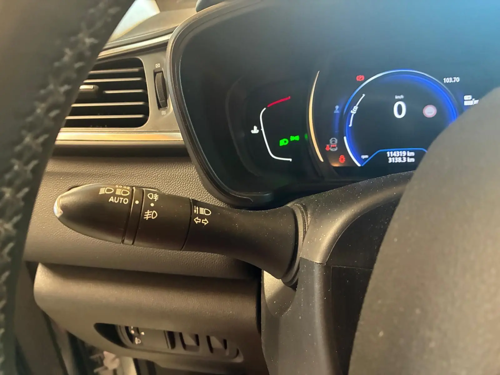 Vue rapprochée du combiné d'instruments et du commodo d'éclairage dans un Renault Kadjar gris, tableau de bord numérique allumé.