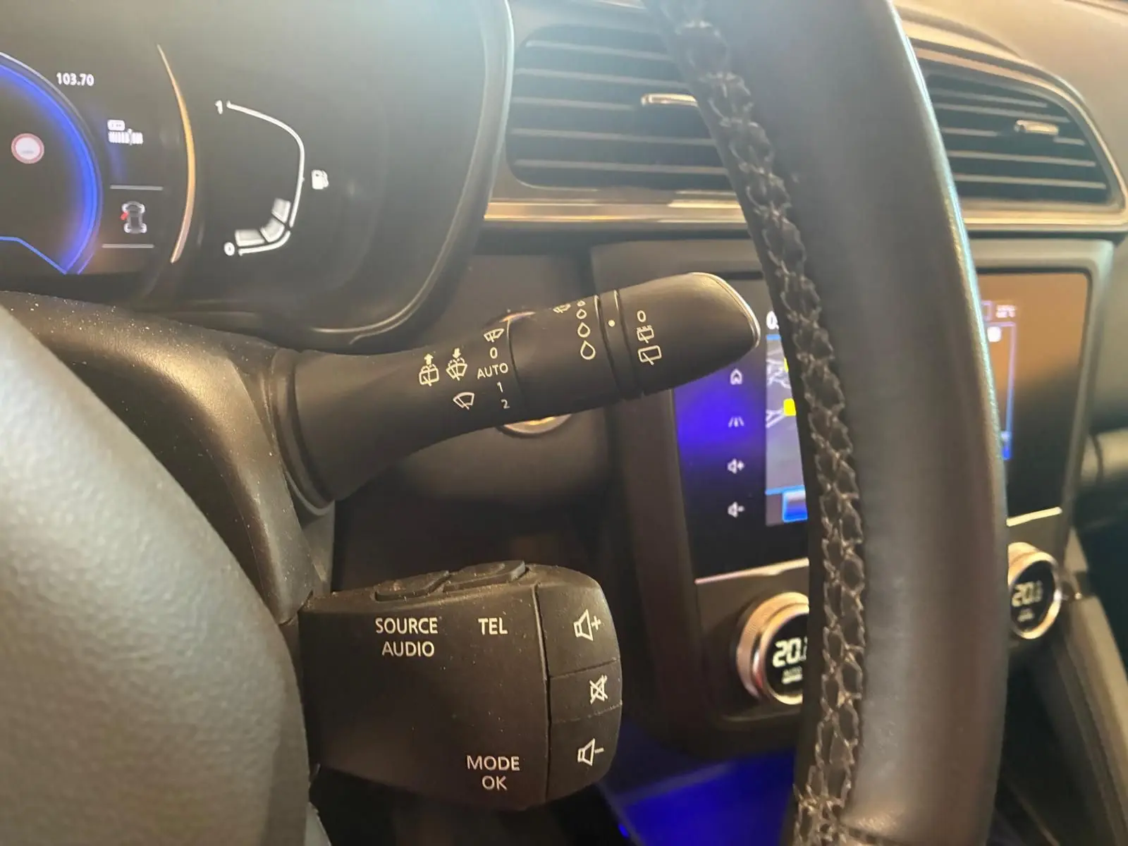Gros plan sur le volant et la commande multifonction du Renault Kadjar gris, tableau de bord et écran tactile en arrière-plan.