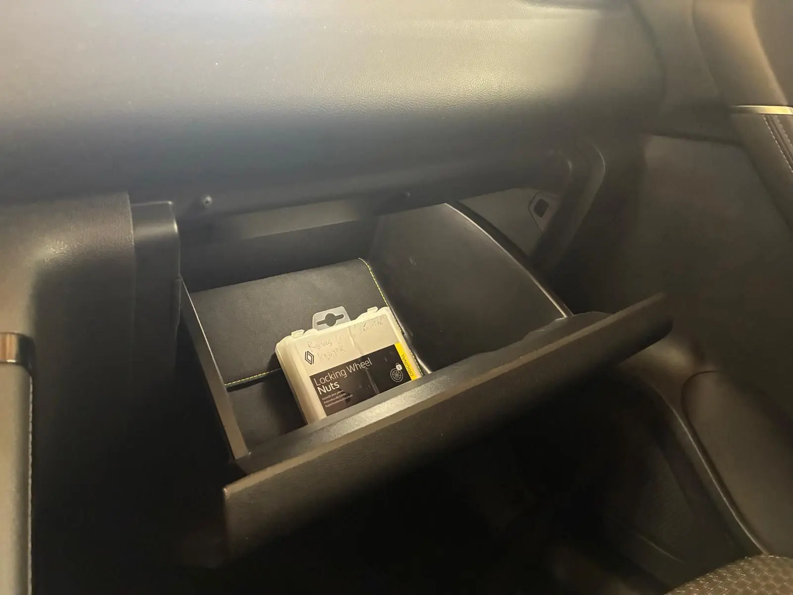 Gant de boîte à gants ouvert côté passager dans un Renault Kadjar gris 2020, avec notice de boulons antivol visible.