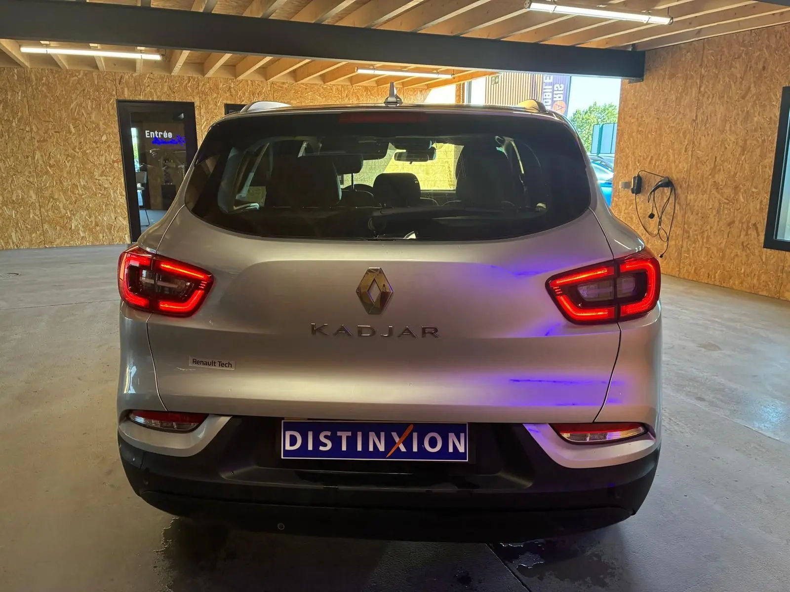 Vue arrière du Renault Kadjar gris 2020 avec feux allumés et logo distinctif dans un garage.